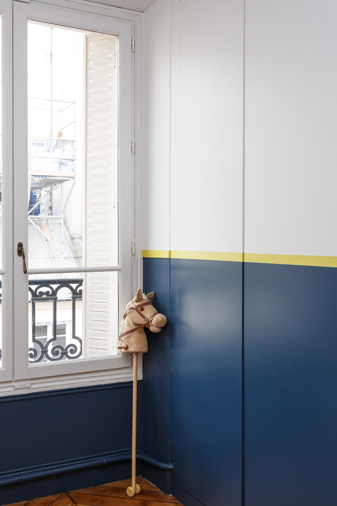 Mid-sized modern kids' bedroom in Paris with blue walls, medium hardwood floors and brown floor for boys.