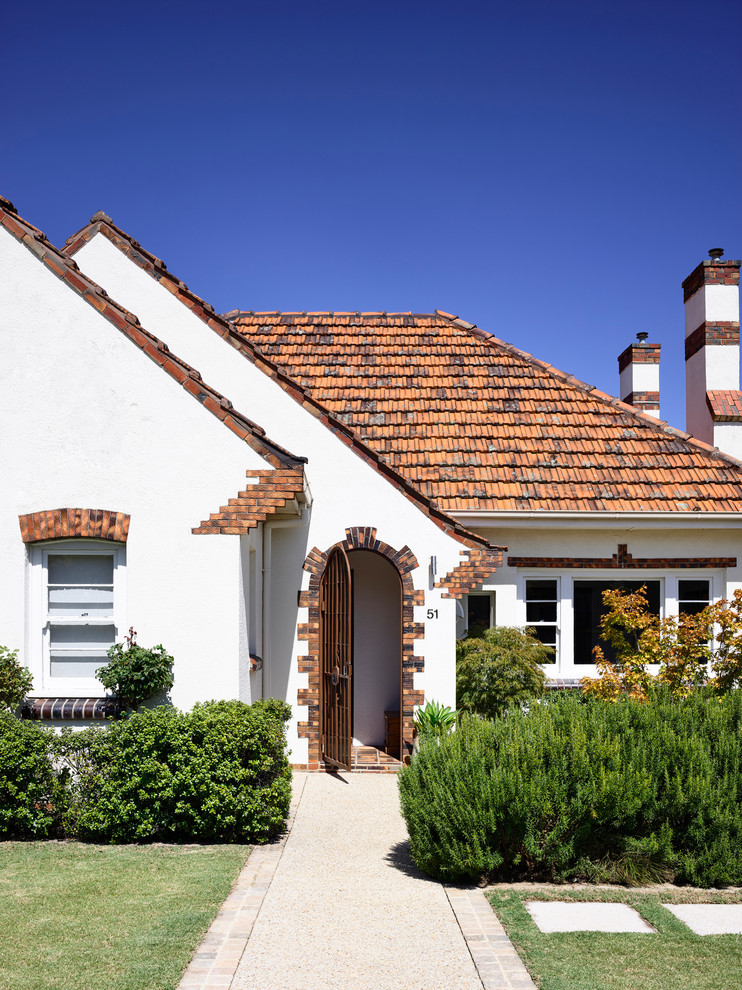 This is an example of a mid-sized traditional two-storey brick white house exterior in Melbourne with a hip roof and a tile roof.