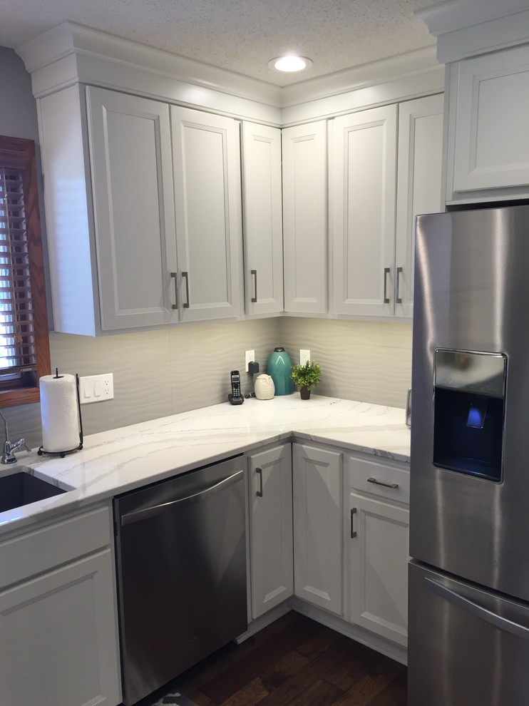 Large transitional l-shaped dark wood floor eat-in kitchen photo with an undermount sink, flat-panel cabinets, white cabinets, quartz countertops, white backsplash, ceramic backsplash, stainless steel appliances and an island