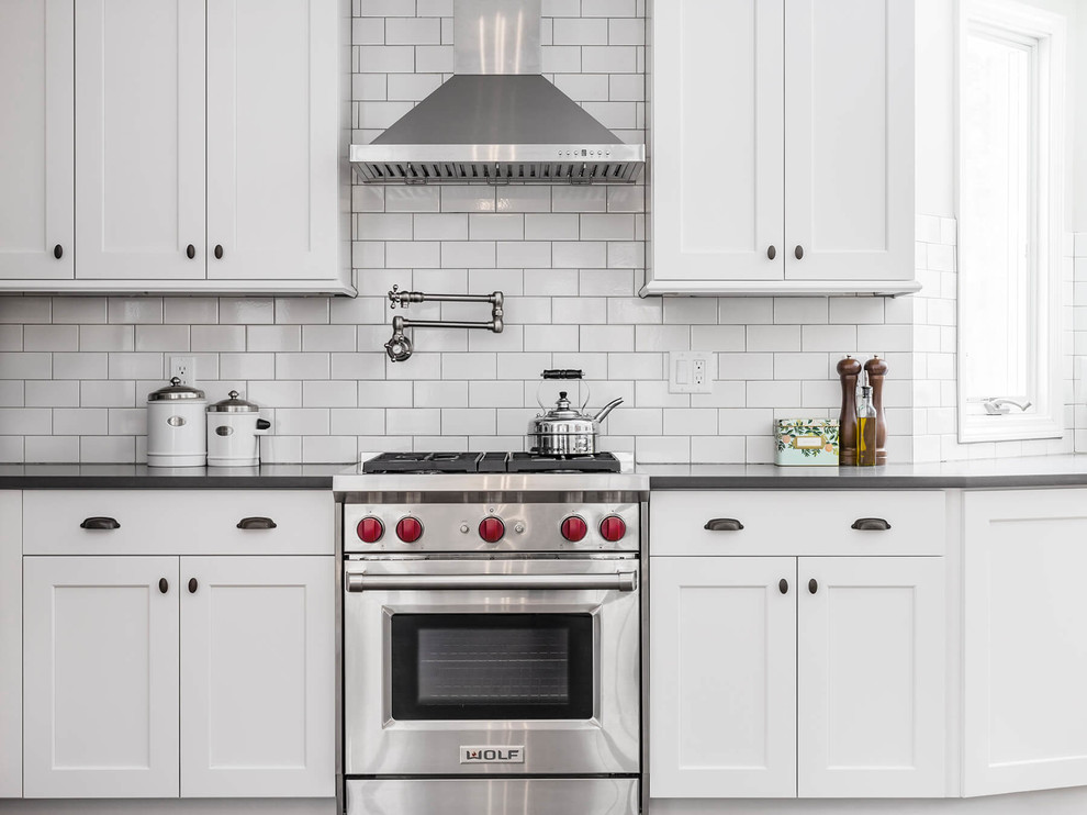 Example of a transitional l-shaped eat-in kitchen design in Providence with a farmhouse sink, shaker cabinets, white cabinets, quartzite countertops, white backsplash, subway tile backsplash, stainless steel appliances and an island