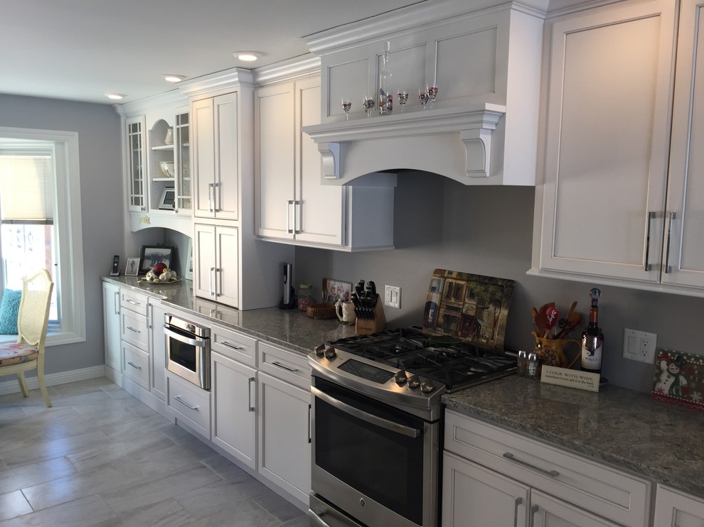 Inspiration for a large transitional l-shaped eat-in kitchen in Other with an undermount sink, shaker cabinets, white cabinets, granite benchtops, stainless steel appliances, porcelain floors, no island and grey floor.