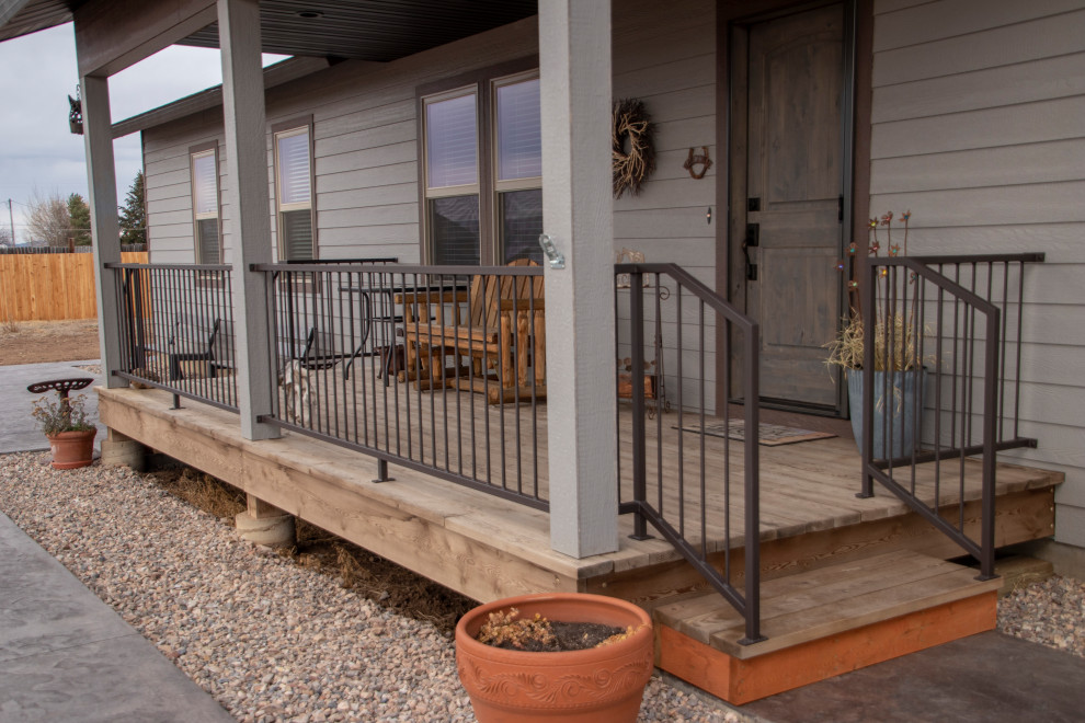 Mid-sized front yard verandah in Other with stamped concrete, an awning and metal railing.