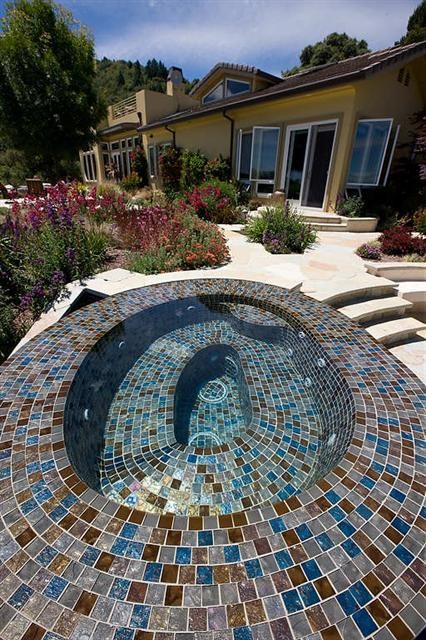 Inspiration for a mid-sized mediterranean backyard custom-shaped infinity pool in San Francisco with natural stone pavers and a hot tub.
