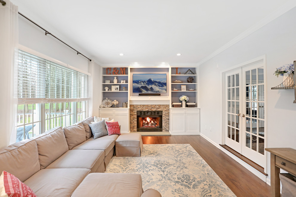 Medium sized classic enclosed games room in New York with white walls, medium hardwood flooring, a standard fireplace, a stacked stone fireplace surround and brown floors.