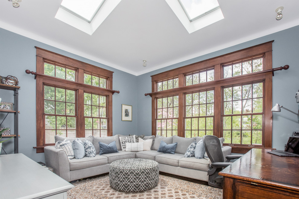 This is an example of a mid-sized transitional enclosed family room in New York with blue walls, dark hardwood floors, no fireplace, a wall-mounted tv and brown floor.
