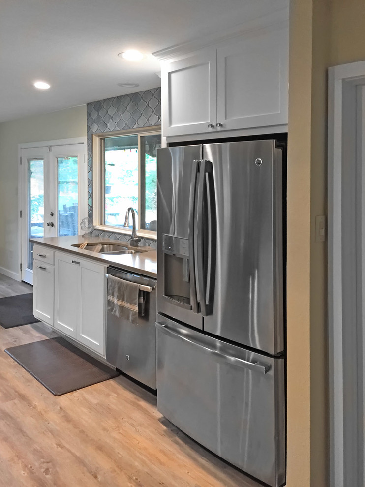 Inspiration for a mid-sized transitional galley vinyl floor and brown floor kitchen pantry remodel with an undermount sink, shaker cabinets, white cabinets, solid surface countertops, blue backsplash, ceramic backsplash, stainless steel appliances and no island