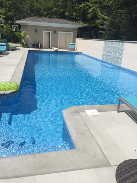 Photo of a small contemporary backyard custom-shaped lap pool in New York with a pool house and stamped concrete.