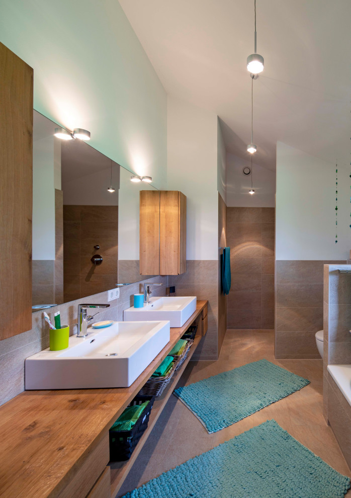 Modernes Badezimmer mit Einbaubadewanne, bodengleicher Dusche, grauen Fliesen, Aufsatzwaschbecken, grauem Boden und offener Dusche in München