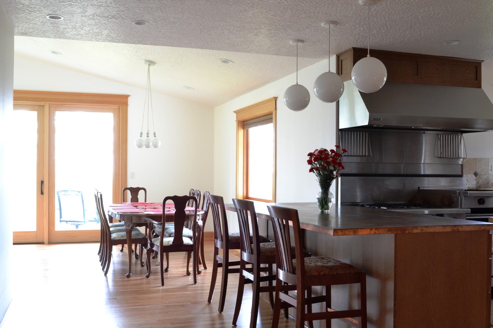 Inspiration for a mid-sized traditional l-shaped open plan kitchen in Portland with an integrated sink, shaker cabinets, brown cabinets, copper benchtops, stainless steel appliances, light hardwood floors and a peninsula.