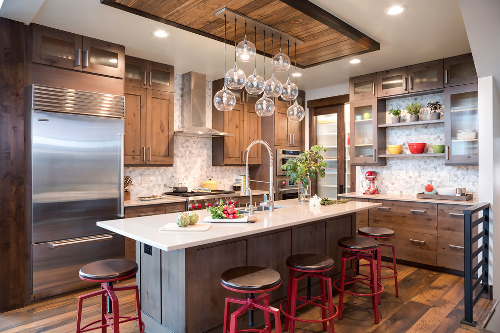 This is an example of a country l-shaped kitchen in Denver with recessed-panel cabinets, medium wood cabinets, white splashback, stainless steel appliances, medium hardwood floors, with island and brown floor.