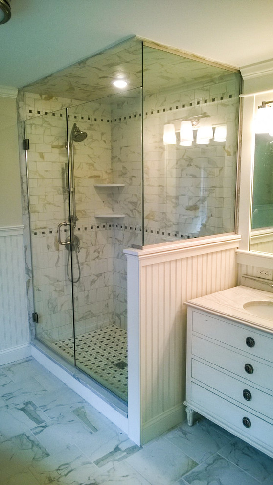 Design ideas for a mid-sized beach style master bathroom in Providence with glass-front cabinets, white cabinets, a drop-in tub, a corner shower, a one-piece toilet, gray tile, porcelain tile, beige walls and plywood floors.