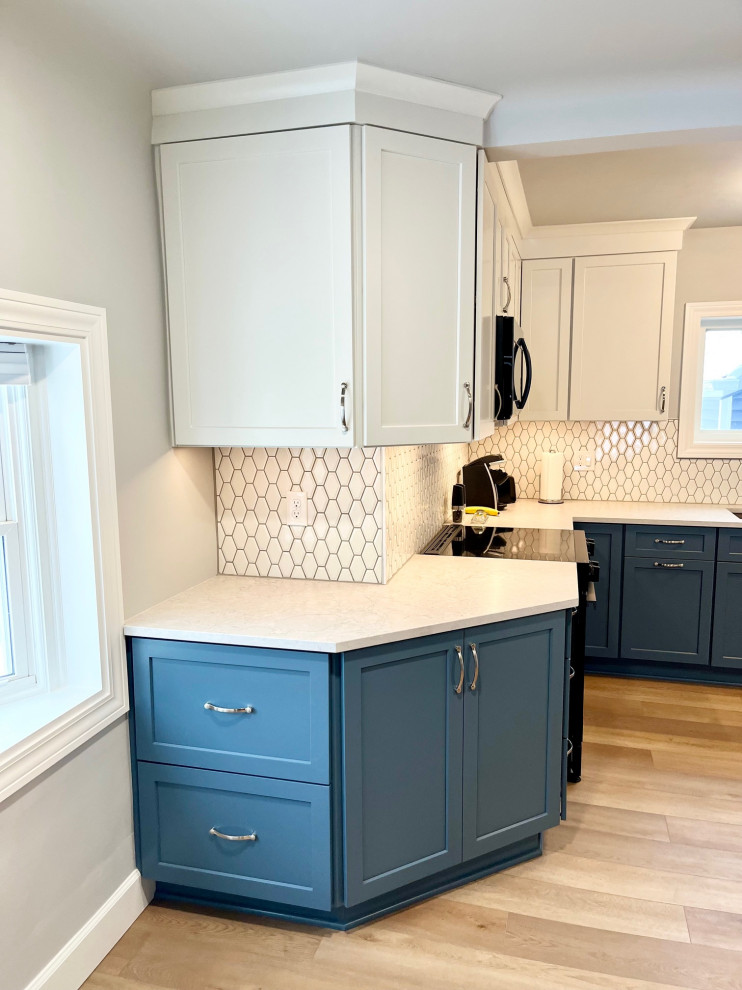 Example of a mid-sized transitional u-shaped vinyl floor and brown floor eat-in kitchen design with an undermount sink, shaker cabinets, white cabinets, quartz countertops, white backsplash, ceramic backsplash, stainless steel appliances, no island and white countertops