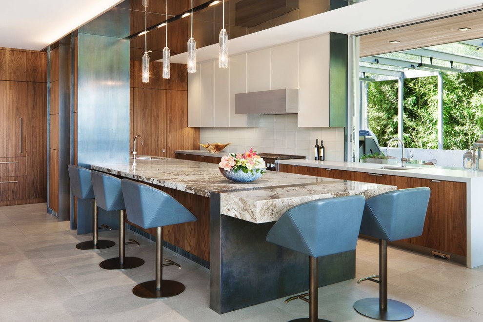 This is an example of an expansive contemporary l-shaped open plan kitchen in Seattle with an undermount sink, flat-panel cabinets, medium wood cabinets, granite benchtops, white splashback, glass tile splashback, stainless steel appliances, porcelain floors, with island, grey floor and grey benchtop.
