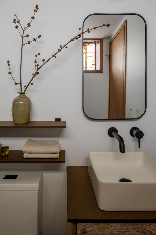 Photo of a small transitional master bathroom in New York with flat-panel cabinets, light wood cabinets, an open shower, a one-piece toilet, beige walls, slate floors, an integrated sink, concrete benchtops, black floor, a shower curtain, grey benchtops, a double vanity, a freestanding vanity and exposed beam.