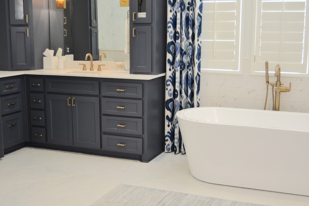 Design ideas for a large transitional master bathroom in Dallas with shaker cabinets, blue cabinets, a freestanding tub, a corner shower, a two-piece toilet, white tile, porcelain tile, white walls, porcelain floors, an undermount sink, engineered quartz benchtops, white floor and a hinged shower door.