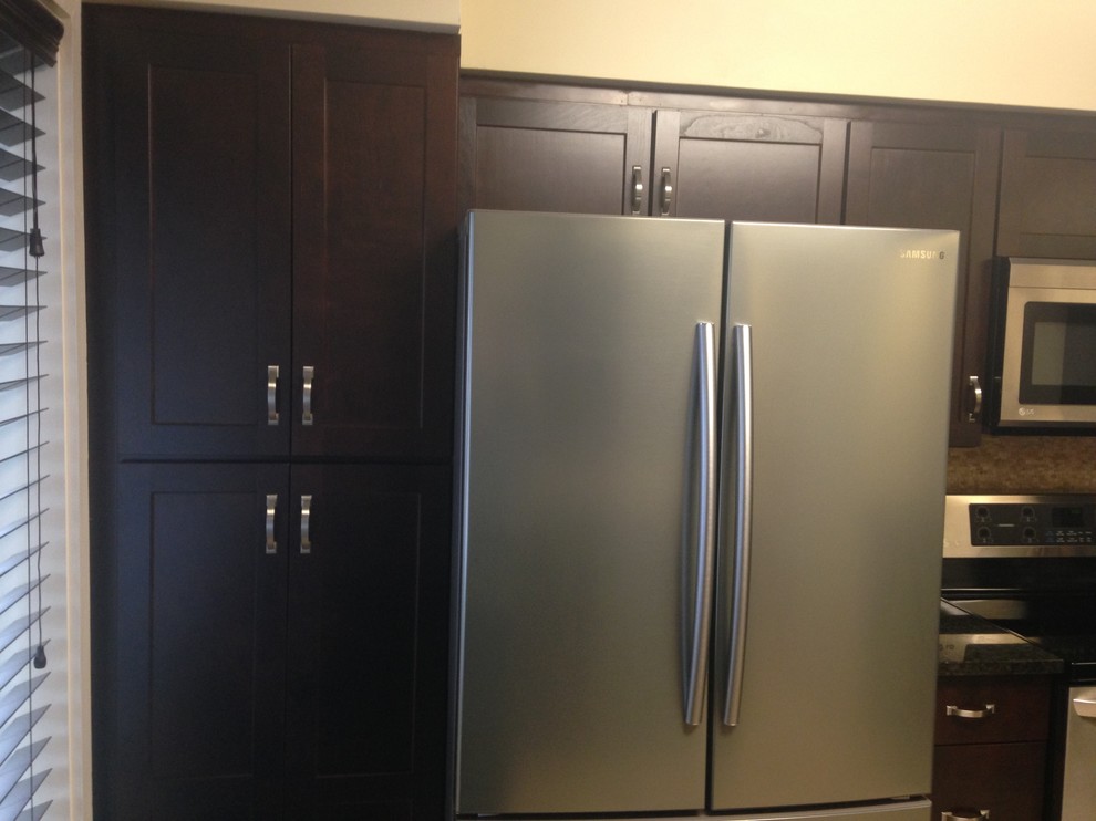 Inspiration for a mid-sized transitional l-shaped porcelain tile enclosed kitchen remodel with an undermount sink, shaker cabinets, dark wood cabinets, granite countertops, beige backsplash, stone tile backsplash, stainless steel appliances and an island