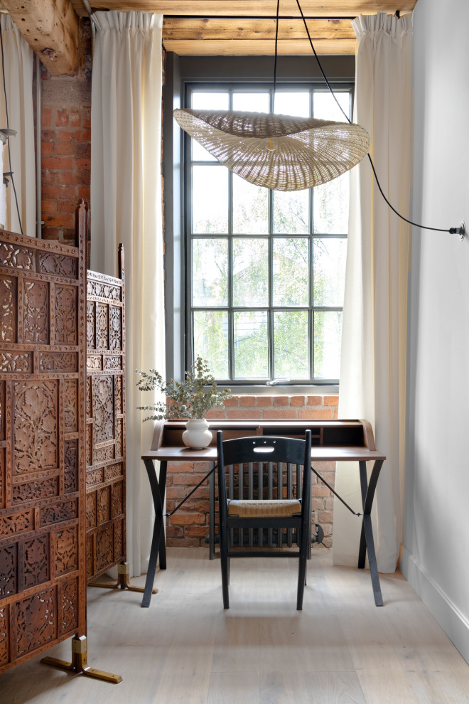 Modelo de despacho rústico pequeño con paredes blancas, suelo de madera en tonos medios, escritorio independiente, suelo marrón, vigas vistas y ladrillo