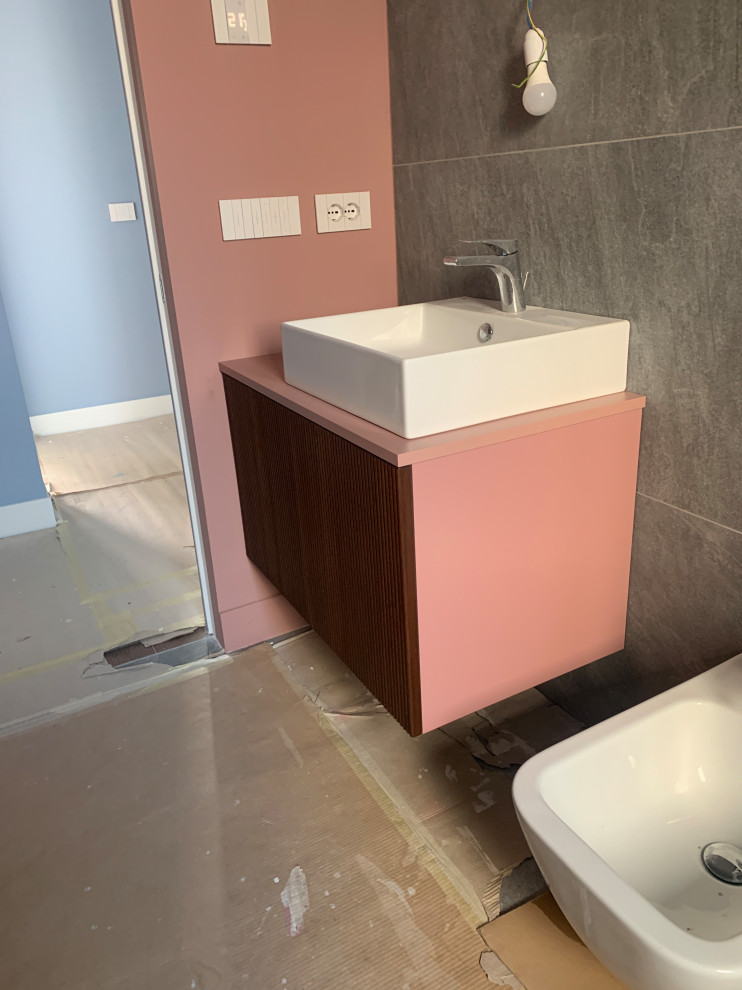 На фото: маленькая, узкая и длинная ванная комната в современном стиле с фасадами с филенкой типа жалюзи, темными деревянными фасадами, душем без бортиков, инсталляцией, серой плиткой, керамогранитной плиткой, розовыми стенами, полом из керамогранита, душевой кабиной, настольной раковиной, столешницей из ламината, серым полом, душем с распашными дверями, розовой столешницей, тумбой под одну раковину и подвесной тумбой для на участке и в саду с