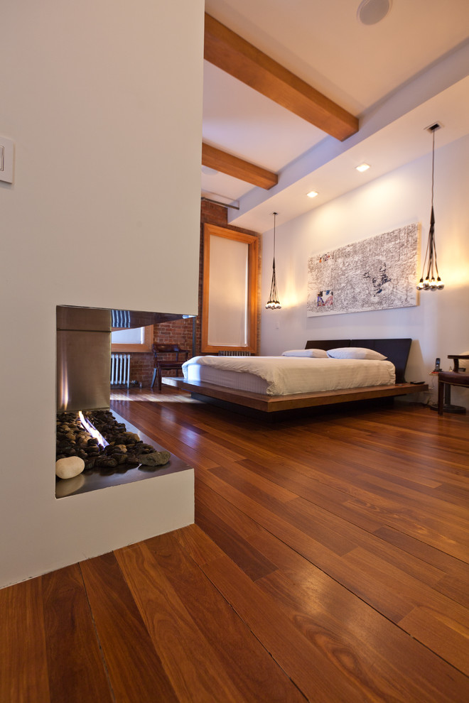 Photo of a contemporary bedroom in New York with white walls and brown floor.