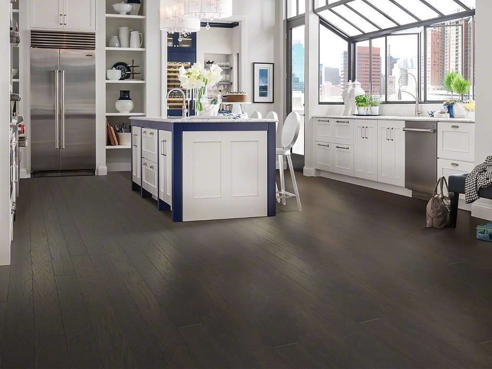 Inspiration for a mid-sized transitional u-shaped dark wood floor enclosed kitchen remodel with an undermount sink, stainless steel appliances, an island, recessed-panel cabinets and white cabinets
