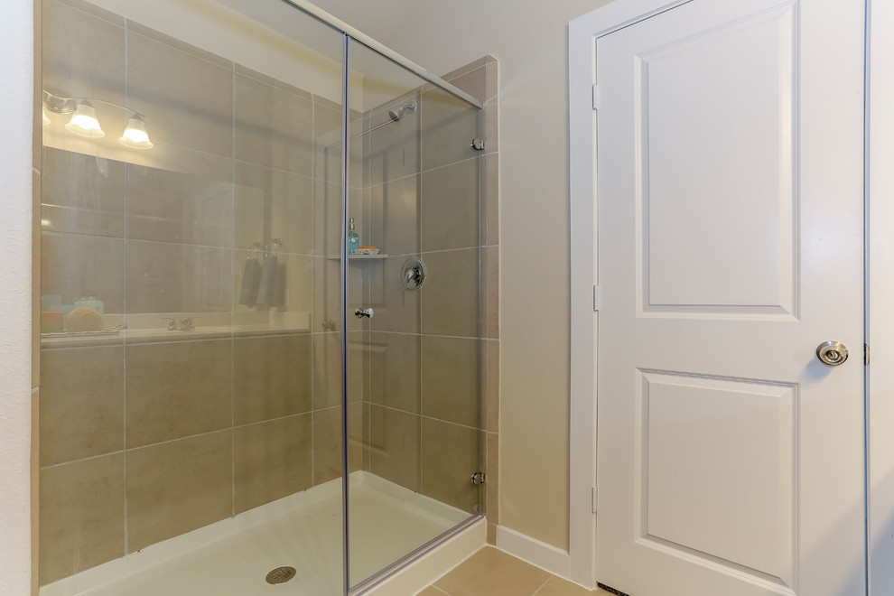 Photo of a large transitional master bathroom in Houston with recessed-panel cabinets, dark wood cabinets, an alcove shower, beige tile, ceramic tile, beige walls, ceramic floors, an integrated sink, solid surface benchtops, beige floor and a hinged shower door.