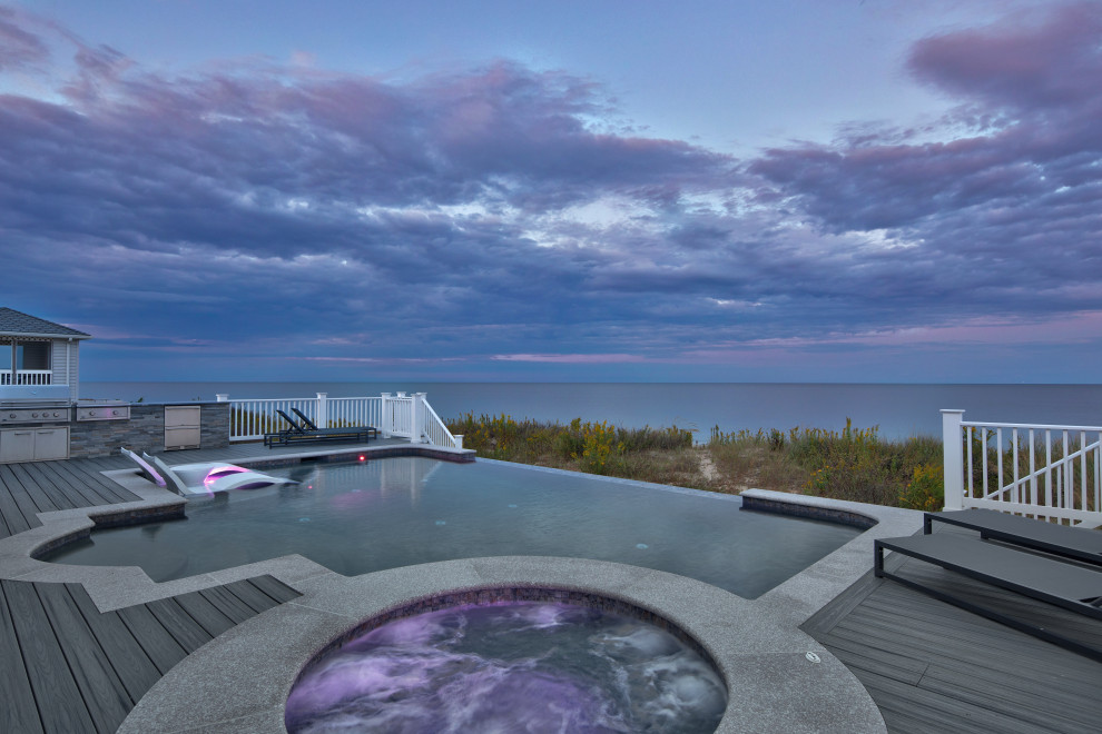 Example of a mid-sized trendy backyard custom-shaped infinity hot tub design with decking