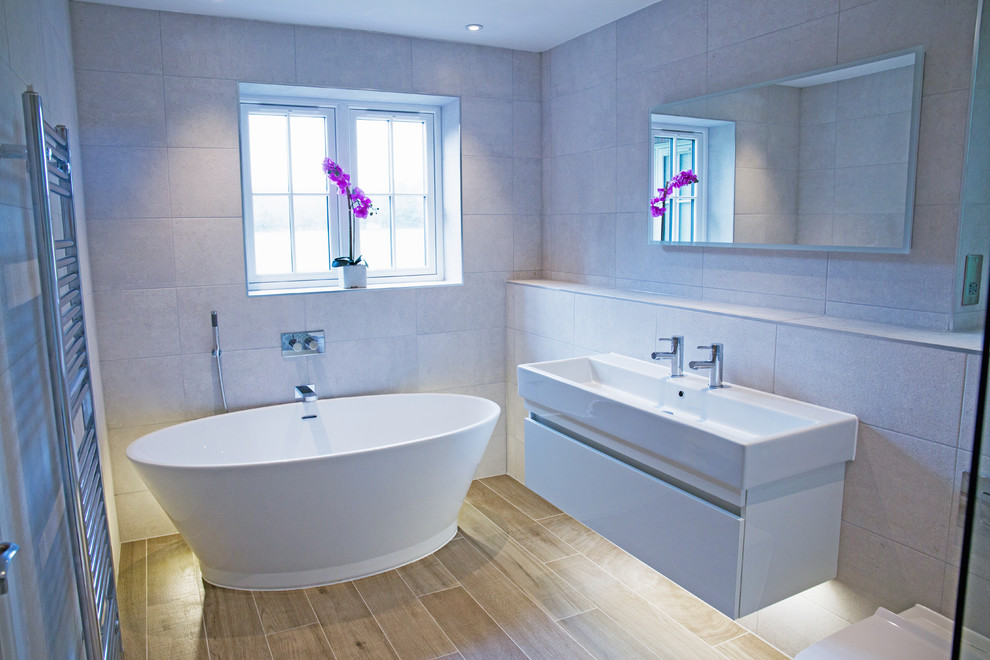 Design ideas for a contemporary bathroom in Hertfordshire with a freestanding tub, an open shower, beige tile, ceramic tile, ceramic floors and a wall-mount sink.