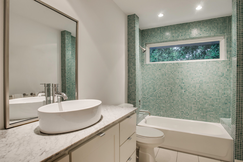 Photo of a mid-sized contemporary 3/4 bathroom in Dallas with shaker cabinets, white cabinets, a freestanding tub, a shower/bathtub combo, a two-piece toilet, green tile, mosaic tile, white walls, ceramic floors, a vessel sink and marble benchtops.