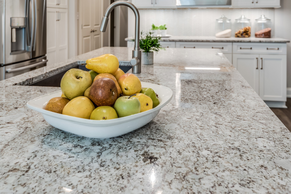 Inspiration for a mid-sized transitional l-shaped open concept kitchen remodel with an undermount sink, flat-panel cabinets, white cabinets, quartz countertops, white backsplash, glass tile backsplash, stainless steel appliances, an island and white countertops