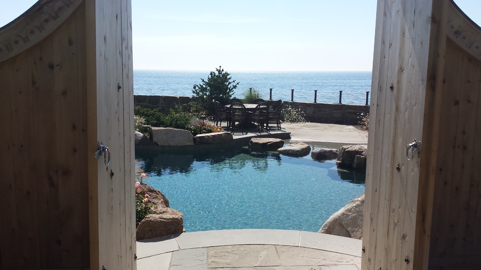 Inspiration for an expansive beach style side yard custom-shaped natural pool in Boston with a water feature and natural stone pavers.