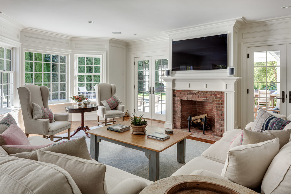 Design ideas for a mid-sized traditional family room in Boston with white walls, medium hardwood floors, a standard fireplace, a brick fireplace surround and a wall-mounted tv.