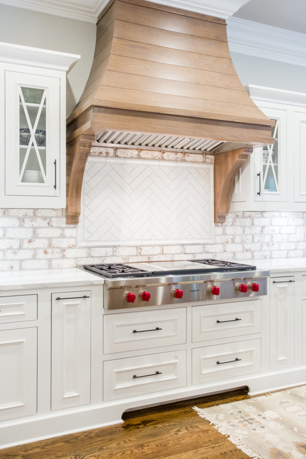 Eat-in kitchen - large transitional u-shaped medium tone wood floor and brown floor eat-in kitchen idea in Atlanta with a farmhouse sink, raised-panel cabinets, white cabinets, quartz countertops, white backsplash, brick backsplash, stainless steel appliances, an island and white countertops