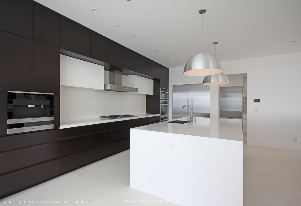 Large contemporary single-wall open plan kitchen in Orange County with an undermount sink, flat-panel cabinets, dark wood cabinets, quartz benchtops, white splashback, porcelain splashback, stainless steel appliances, limestone floors and with island.