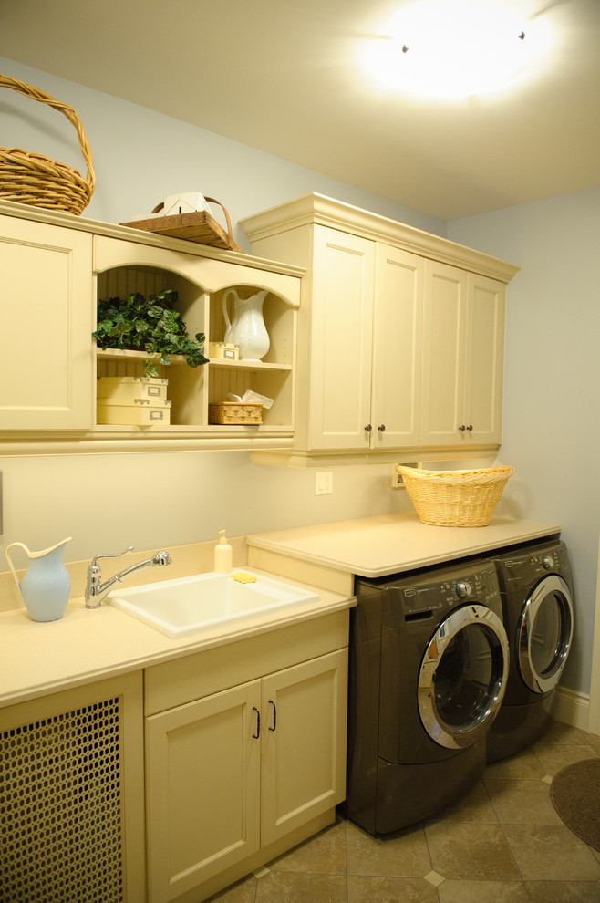 This is an example of a mid-sized country single-wall utility room in Toronto with a drop-in sink, shaker cabinets, white cabinets, beige walls and slate floors.