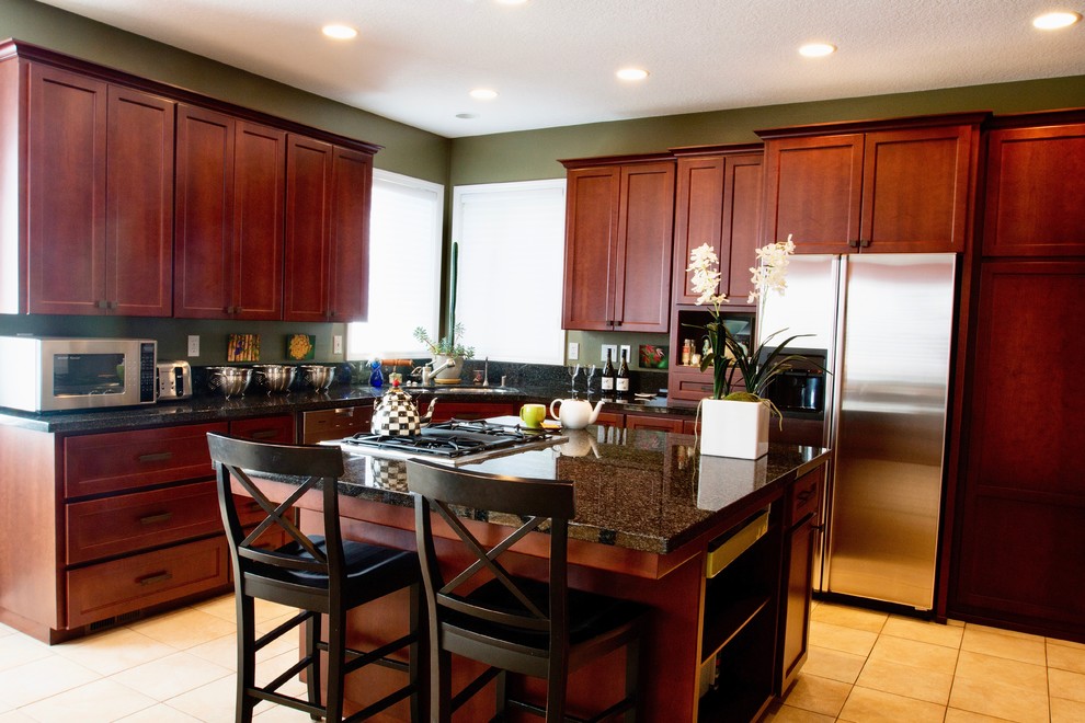 Large eclectic u-shaped ceramic tile eat-in kitchen photo with a double-bowl sink, recessed-panel cabinets, dark wood cabinets, granite countertops, black backsplash, stone slab backsplash, stainless steel appliances and an island