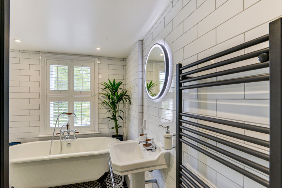 Medium sized victorian bathroom in Sussex with a freestanding bath, a corner shower, a two-piece toilet, white tiles, ceramic tiles, white walls, ceramic flooring, a pedestal sink, tiled worktops, multi-coloured floors, a sliding door, black worktops, feature lighting and a single sink.