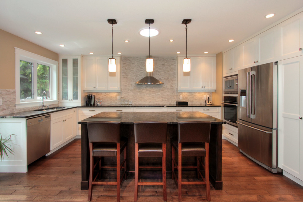 Eat-in kitchen - mid-sized transitional u-shaped medium tone wood floor eat-in kitchen idea in Vancouver with an undermount sink, recessed-panel cabinets, white cabinets, granite countertops, beige backsplash, glass tile backsplash, stainless steel appliances and an island