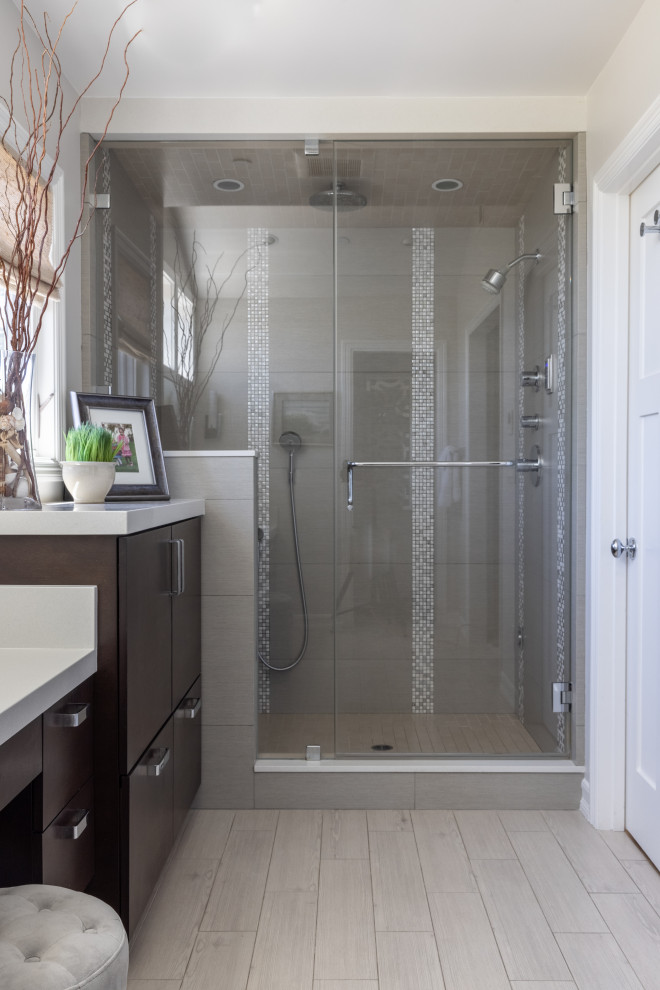 This is an example of a small contemporary master bathroom in San Francisco with flat-panel cabinets, dark wood cabinets, an alcove shower, a one-piece toilet, gray tile, porcelain tile, a trough sink, engineered quartz benchtops, multi-coloured floor, a hinged shower door, white benchtops, an enclosed toilet, a single vanity, a floating vanity and vaulted.
