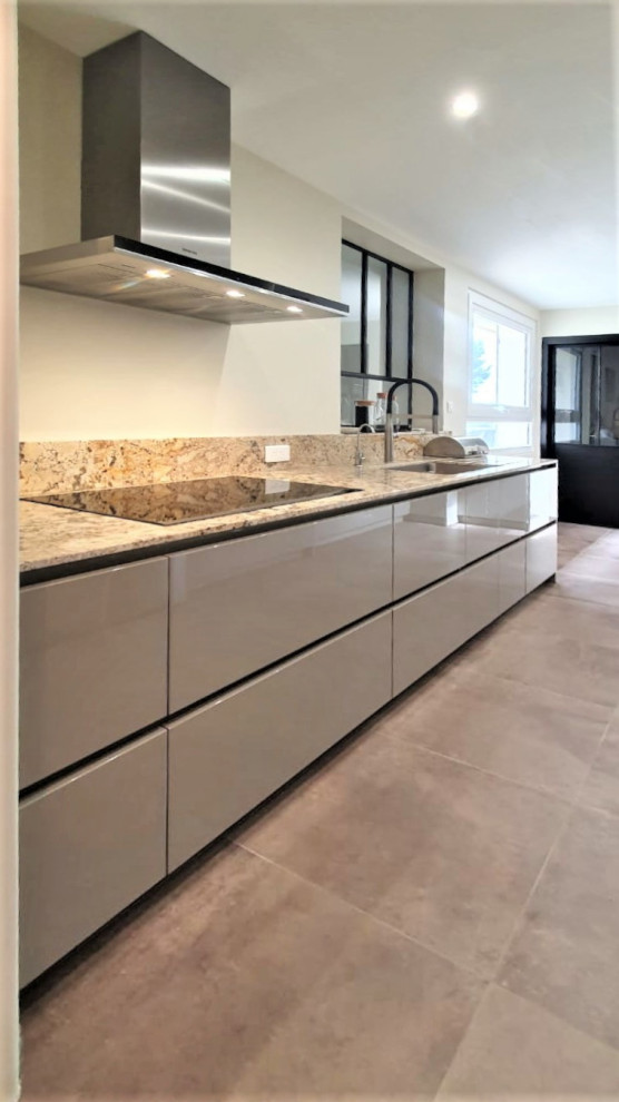 Inspiration for an expansive modern single-wall open plan kitchen in Other with an integrated sink, flat-panel cabinets, beige cabinets, composite countertops, brown splashback, stone slab splashback, integrated appliances, cement flooring, grey floors and brown worktops.