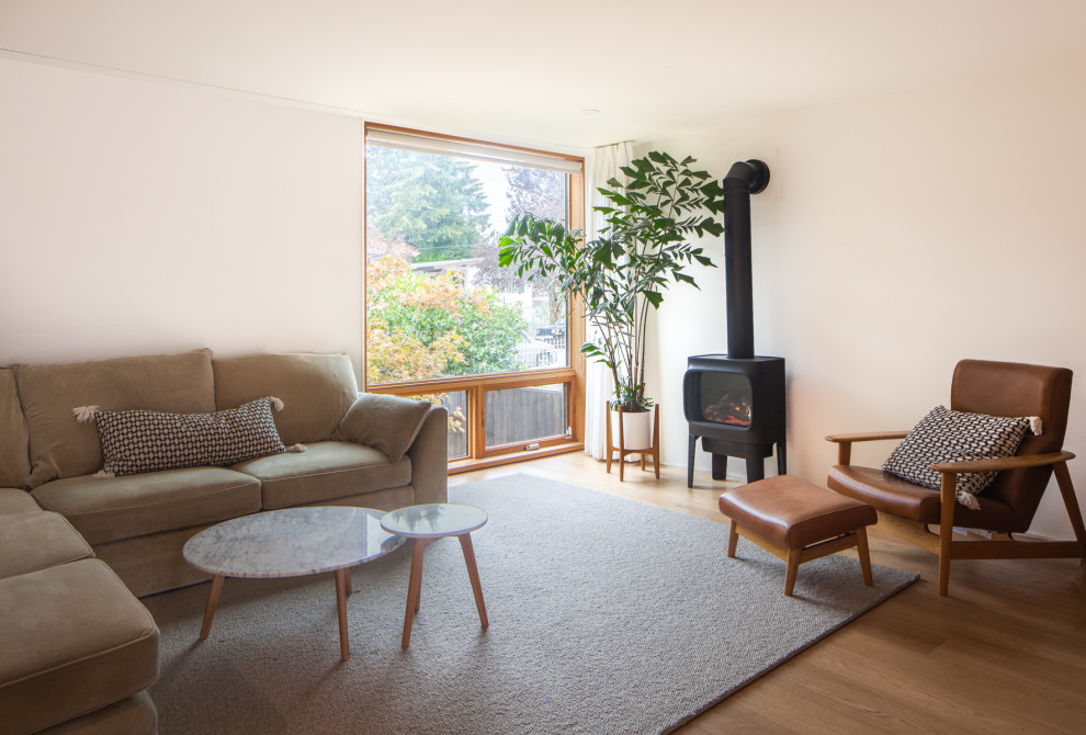Modern living room in Vancouver with beige walls, medium hardwood floors and a hanging fireplace.