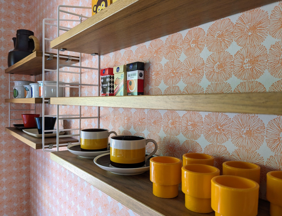 Foto di una sala da pranzo aperta verso la cucina minimalista di medie dimensioni con pareti arancioni e carta da parati