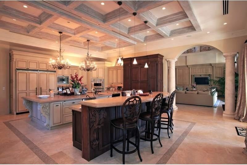 Design ideas for an expansive beach style galley eat-in kitchen in Other with a drop-in sink, beaded inset cabinets, beige cabinets, marble benchtops, stainless steel appliances, travertine floors and multiple islands.