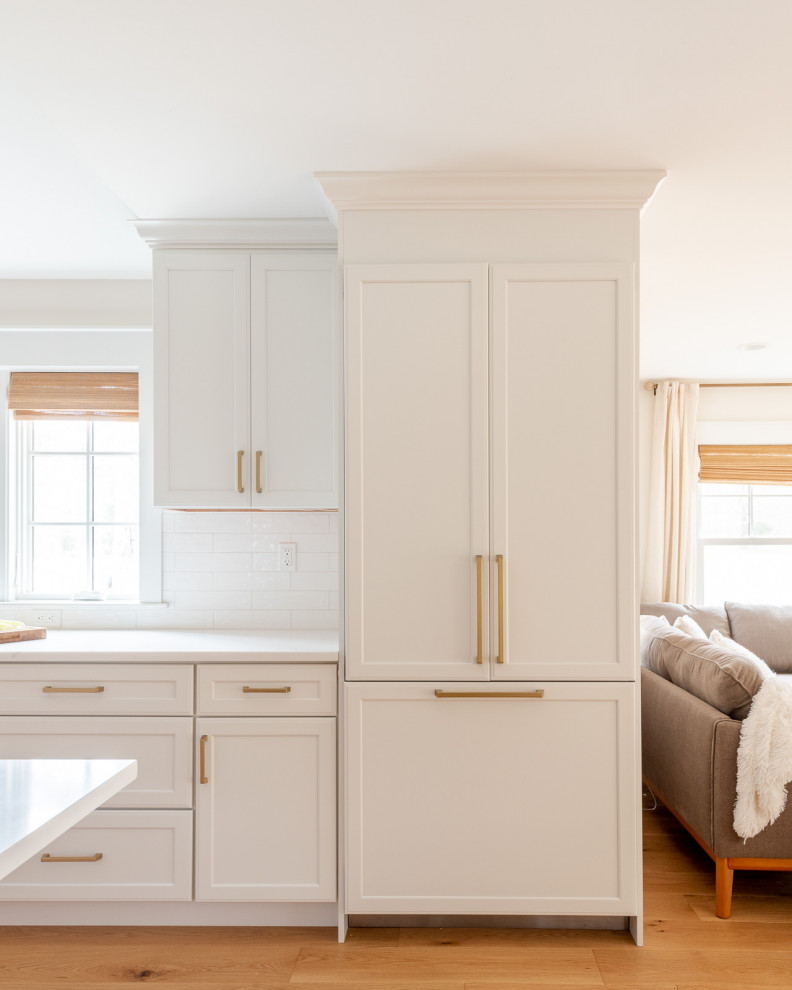 Eat-in kitchen - huge transitional l-shaped light wood floor, brown floor and vaulted ceiling eat-in kitchen idea in Boston with an undermount sink, shaker cabinets, white cabinets, quartz countertops, white backsplash, ceramic backsplash, paneled appliances, an island and white countertops