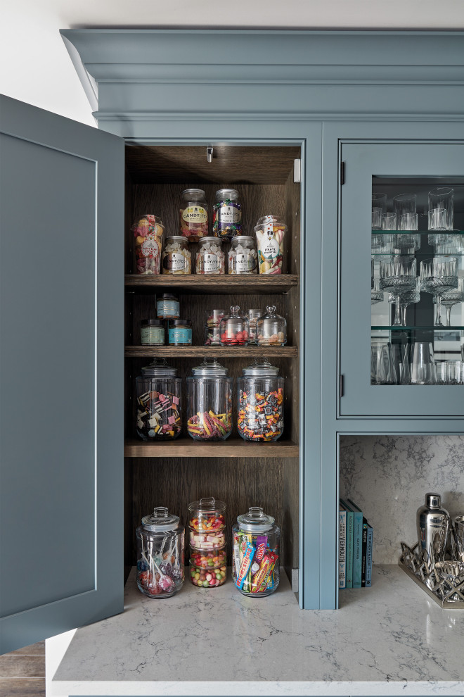 Große Moderne Küche mit Schrankfronten im Shaker-Stil, blauen Schränken, Küchengeräten aus Edelstahl, Kücheninsel, braunem Boden und weißer Arbeitsplatte in Sonstige