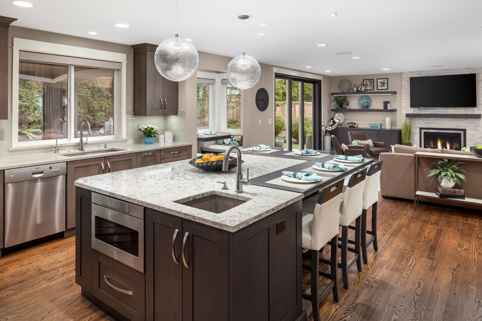 Example of a large transitional u-shaped medium tone wood floor and brown floor eat-in kitchen design in Seattle with a single-bowl sink, shaker cabinets, dark wood cabinets, quartzite countertops, gray backsplash, glass tile backsplash, stainless steel appliances, an island and white countertops