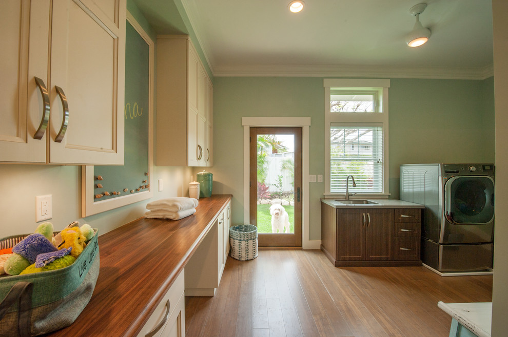 Mid-sized transitional utility room in Hawaii with an undermount sink, white cabinets, wood benchtops, green walls, bamboo floors, a side-by-side washer and dryer and recessed-panel cabinets.