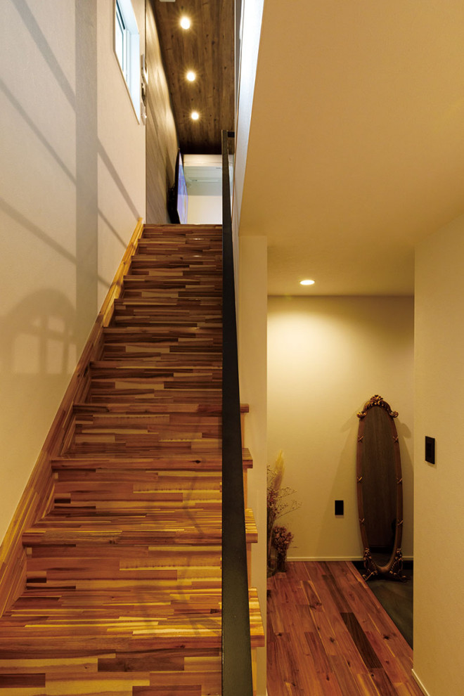 Small modern wood straight staircase in Tokyo with wood risers, metal railing and wallpaper.