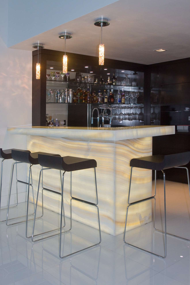 Contemporary u-shaped seated home bar in Miami with dark wood cabinets, mirror splashback and white floor.