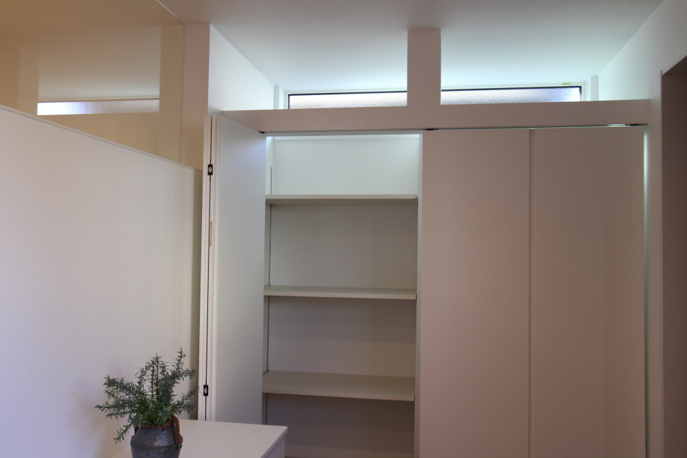 Immagine di una porta d'ingresso minimalista con pareti bianche, pavimento in cemento, una porta singola, una porta nera, pavimento grigio, soffitto in carta da parati, carta da parati e armadio