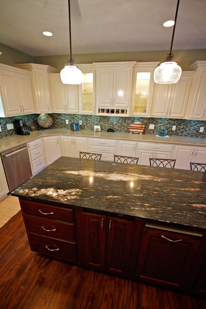 Example of a large u-shaped medium tone wood floor open concept kitchen design with a drop-in sink, raised-panel cabinets, white cabinets, multicolored backsplash, glass tile backsplash, stainless steel appliances and an island